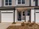 Charming townhome front entrance with gray siding, white trim, a blue front door and attached garage at 8021 Lerwick Trl, Charlotte, NC 28269