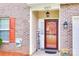 Inviting entryway with stylish door, sidelight window, hanging lantern, brick facade, and a 'Hey Friends' sign at 10071 Highland Creek Cir, Indian Land, SC 29707