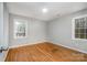 Bedroom with hardwood floors, neutral walls, and natural light streaming through two windows at 1024 Eaglewood Ave, Charlotte, NC 28212