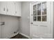 Functional laundry room with white cabinets, tile flooring, and exterior access at 1024 Eaglewood Ave, Charlotte, NC 28212