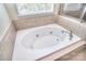 Close-up of a pristine white soaking tub with jacuzzi jets, surrounded by neutral tile at 1100 Millbank Dr, Matthews, NC 28104