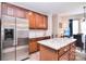 Granite kitchen island with stainless steel fridge and wood cabinetry with eat-in breakfast nook at 1100 Millbank Dr, Matthews, NC 28104