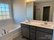 Bathroom featuring gray tile, double sink vanity with white quartz countertop, large window and soaking tub at 117 High Rock Ct # 9, Statesville, NC 28677