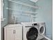 Well-lit laundry room with washer, dryer, sink, and storage shelves at 20313 Queensdale Dr, Cornelius, NC 28031