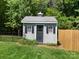 Backyard shed in well-maintained yard with white picket fence and surrounding trees at 4323 Wiregrass Rd, Indian Land, SC 29707