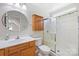 Well-lit bathroom includes a wood vanity, round mirror, and shower with sliding glass doors at 4323 Wiregrass Rd, Indian Land, SC 29707