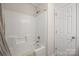Bright white bathroom showcases a tiled tub-shower combination and a door at 4323 Wiregrass Rd, Indian Land, SC 29707