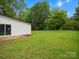 Large backyard featuring lush green grass and mature trees. Sliding glass door provides access at 5316 Rupert Ln, Charlotte, NC 28215