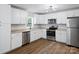 A modern kitchen featuring stainless steel appliances, white cabinetry, granite countertops, and wood-look flooring at 5316 Rupert Ln, Charlotte, NC 28215