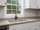 Close-up of a kitchen sink with a black faucet, granite countertops, and white cabinets at 5316 Rupert Ln, Charlotte, NC 28215