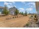 A sloped backyard features young trees and landscaping beneath a bright, cloudy sky at 6419 Cambridge Dr, Harrisburg, NC 28075