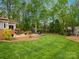 Expansive backyard featuring a deck, firepit area, manicured lawn, and mature trees, perfect for outdoor enjoyment at 9009 Stourbridge Dr, Huntersville, NC 28078