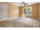 Cozy bedroom features plush carpet, ceiling fan, and ample natural light from a large window at 9009 Stourbridge Dr, Huntersville, NC 28078