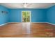 Empty blue room with hardwood floors, ceiling fan, and sliding doors to a small deck at 9009 Stourbridge Dr, Huntersville, NC 28078