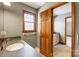 Bathroom featuring neutral gray wall, wood trim, window, wood door, granite countertop and white sink at 9951 Providence Forest Ln, Charlotte, NC 28270