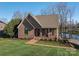 Charming brick home featuring a red door, manicured lawn, and view of the lake at 108 N Oakwood Dr, Kings Mountain, NC 28086