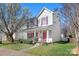 Charming two-story home with red shutters and a welcoming front porch surrounded by lush greenery and blooming trees at 12419 Swan Wings Pl, Huntersville, NC 28078