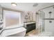 Bright bathroom featuring a soaking tub, glass-enclosed shower, and a double sink vanity with modern finishes at 13732 Strathaven Dr, Matthews, NC 28105