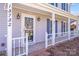 Home's charming front porch with a white railing, a decorative front door, and exterior lights at 13732 Strathaven Dr, Matthews, NC 28105