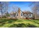 Back exterior featuring a stone chimney, steps down to the lawn, and mature trees at 147 Pearl Bay Dr, New London, NC 28127