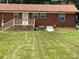 Expansive backyard featuring a brick house with an unfinished wood deck and a well-maintained lawn at 213 Crowell Ave, Albemarle, NC 28001