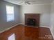 Cozy living room featuring a traditional brick fireplace and gleaming hardwood floors at 213 Crowell Ave, Albemarle, NC 28001