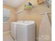 Bright laundry room featuring white washer and dryer set with wire shelving and neutral walls at 3034 Oakmere Rd, Waxhaw, NC 28173