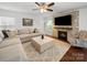 Inviting living room featuring a stacked stone fireplace, plush seating, and a ceiling fan at 4127 Stacy Blvd, Charlotte, NC 28209