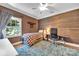 This is a bedroom that includes a wood accent wall, a patterned rug, a window, and ceiling fan at 4536 Rustling Woods Dr, Denver, NC 28037