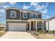 Charming two-story home with a covered porch, stone accents, a two-car garage, and a beautifully landscaped front yard at 5013 Dunsford Dr, Denver, NC 28037