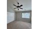 A cozy bedroom featuring a ceiling fan, window and plush carpet at 9130 Charminster Ct, Charlotte, NC 28269