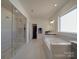 Bright bathroom with soaking tub, glass shower, and neutral tile at 9786 Verdun Ct, Fort Mill, SC 29707