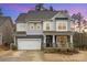 Two-story home featuring gray siding, a covered porch with rocking chairs, and a two-car garage at 1004 Whipcord Dr, Waxhaw, NC 28173