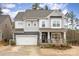 Charming two-story home featuring a stone facade, covered porch with rocking chairs and a two car garage at 1004 Whipcord Dr, Waxhaw, NC 28173