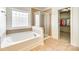 Bathroom featuring a soaking tub under a window and glass-doored shower with tile surround at 10123 Barrands Ln, Charlotte, NC 28278