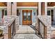 Covered front porch and wood framed double doors of home's entrance with stone columns at 188 Winding Forest Dr, Troutman, NC 28166