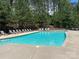A community pool with lounge chairs and tables, surrounded by lush greenery and a secure fence at 188 Winding Forest Dr, Troutman, NC 28166