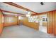 Spacious living room with wood paneling, ceiling fan, carpeted floors, and access to an adjacent kitchen area at 2300 Highlawn Dr, Charlotte, NC 28212