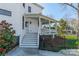 This view of the home displays a covered porch with white railings, steps, and manicured bushes at 234 N Race St, Statesville, NC 28677