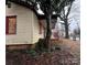 Side view of neglected home with boarded up windows and overgrown yard at 2501 Booker Ave, Charlotte, NC 28216