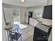 Kitchen with stainless steel appliances, white cabinets, access door to back yard, and new wood floors at 507 E Maple Ave, Gastonia, NC 28054