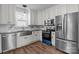 White kitchen with stainless steel appliances, farmhouse sink, dark granite countertops, and wood-look flooring at 512 Washington St, Cramerton, NC 28032