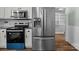 Stainless steel refrigerator and black oven set between white cabinets, with granite countertops and tile backsplash at 512 Washington St, Cramerton, NC 28032