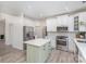 Modern kitchen features a center island with white cabinets and stainless steel appliances at 6087 Diamond Pl, Harrisburg, NC 28075