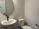 Modern half bathroom with pedestal sink, black faucet, round mirror, and white toilet at 619 Amberjack Pl, York, SC 29745