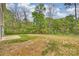 Large grassy backyard area with bordering mature trees and a patio at 8029 Joy Crossing Ln, Charlotte, NC 28214