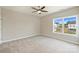 Bright bedroom with plush carpet, ceiling fan, and large window showing neighborhood views at 8029 Joy Crossing Ln, Charlotte, NC 28214