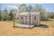 Tan shed featuring a sturdy metal roof, white trim, and a welcoming wooden deck, set against a backdrop of blooming trees at 815 Foxmeade Ct, Salisbury, NC 28144