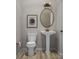 Cozy powder room with pedestal sink, round mirror, and decorative artwork creating an elegant and functional space at 8947 Nettleton Ave, Charlotte, NC 28215