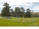 Spacious front yard enclosed by a white fence and featuring mature trees in a park-like setting at 11215 Idlewild Rd, Matthews, NC 28105